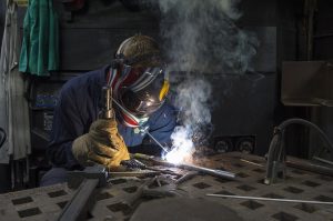 A man welding a piece of metal on a welding table.
